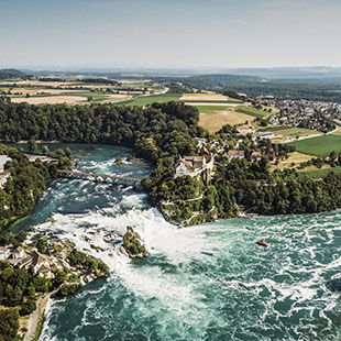 Vista Aérea de un crucero fluvial por el río Rin acercándose a las cataratas en Suiza